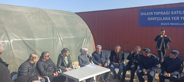 Çadırın önünde oturan vatandaşlar, görevliler