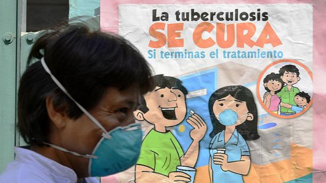 Uma pessoa no Peru passa uma placa que diz "tuberculose está curada"