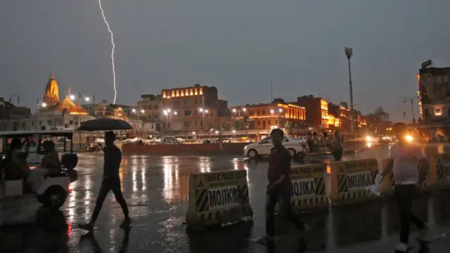 Raio cruza o céu na cidadeslot vencedoresJaipur, na Índia, enquanto pessoas caminham numa rua sob a chuva