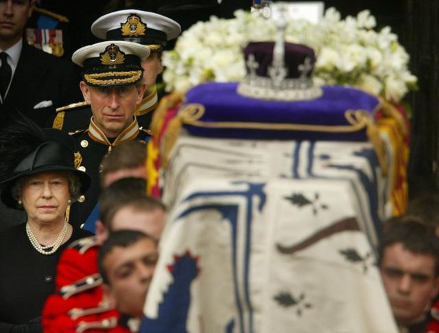 A rainha e o príncipe de Gales caminham ao lado do caixão da rainha-mãe, em 2002.