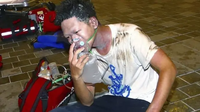 An injured man sits on the ground outside a station after an explosion on a passenger train in Taipei, Taiwan, Thursday, July 7, 2016