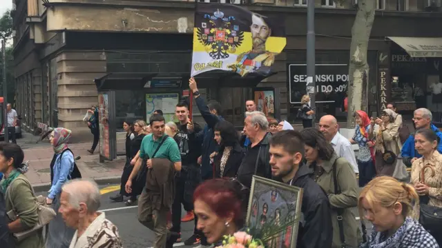 Људи шетају улицом и носе заставу царске Русије