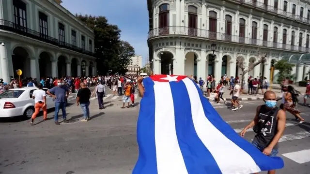 Manifestante segura bandeira de Cuba, em apoio ao governo