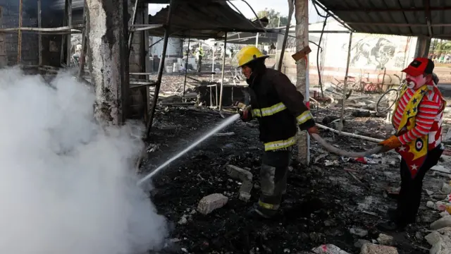 Un bombero y una persona disfrazada de payaso intentan apagar el incendio.