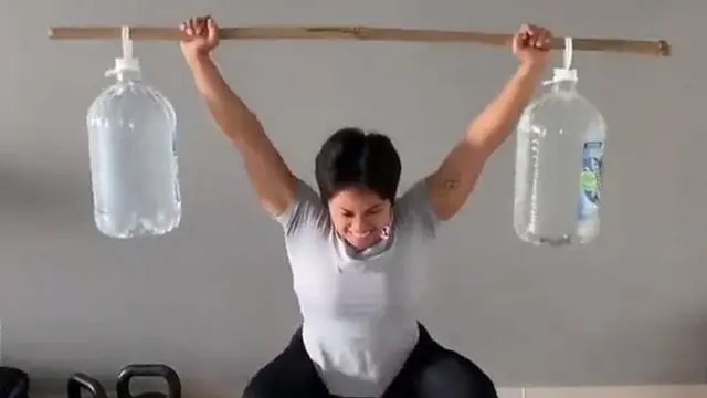 Hidilyn Diaz lifting makeshift weights made from bamboo sticks and water bottles.