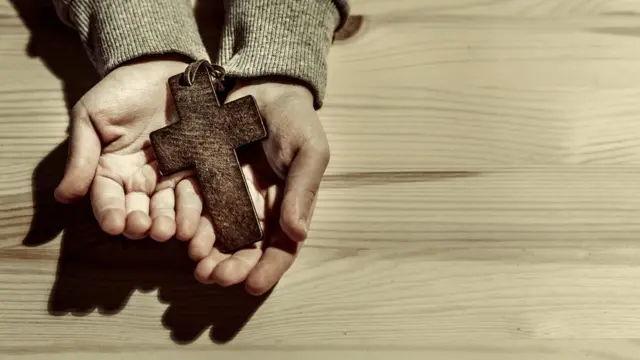 Mano de varón con una cruz.