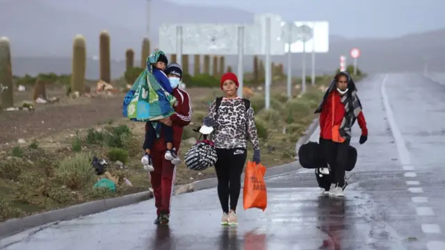 Uma famíliamigrantes venezuelana caminha na fronteira entre o Chile e a Bolívia