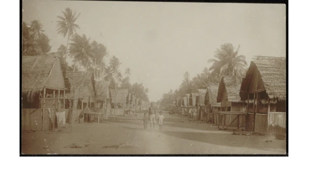 Foto hitam putih di perkampungan. Di tengah terdapat seorang pria bersama dua anaknya