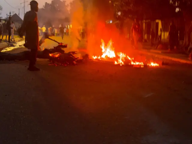 Des pneus et des troncs d'arbre brûlés par des manifestants sur une route
