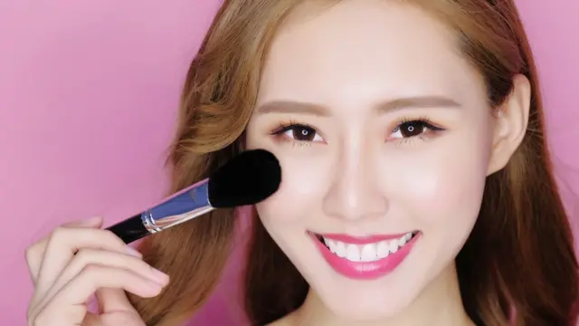 Mujer china maquillándose con una brocha.