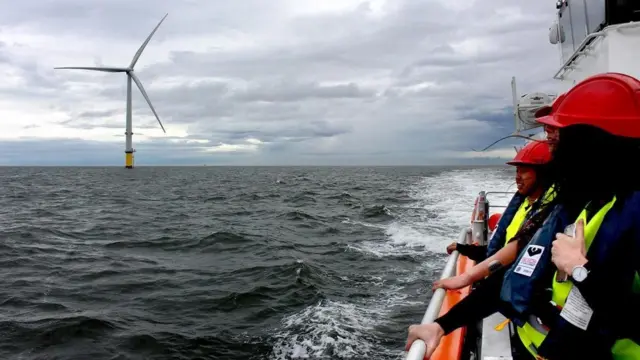 مجموعة من عمال الصيانة بالقرب من أحد توربينات الهواء