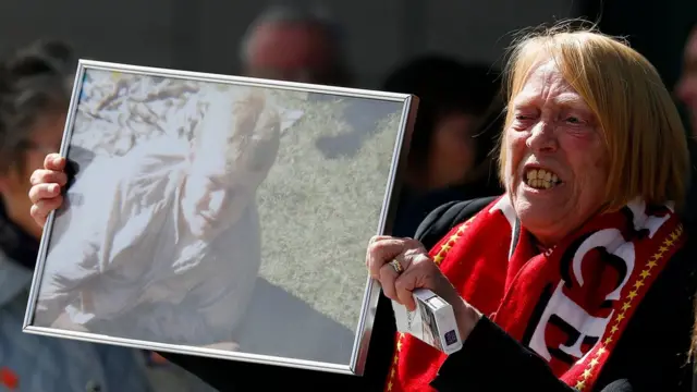 事故で亡くなったキース・マグラスさんの遺影を掲げる遺族
