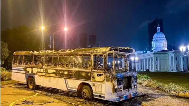 মাহিন্দা রাজপাকশার সরকারি বাসভবনের সামনে আগুনে পুড়িয়ে দেয়া একটি বাস।
