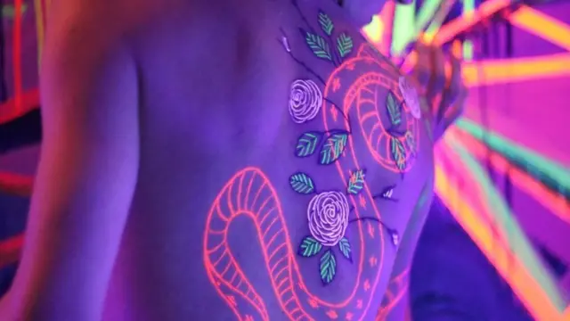 Tattoo karya seniman Kayla Newell yang menyala di bawah sinar UV.