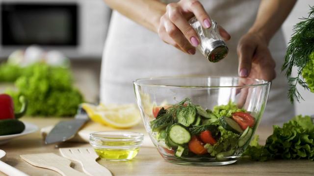 Mãobet nacional appmulher segurando saleiro e salgando salada