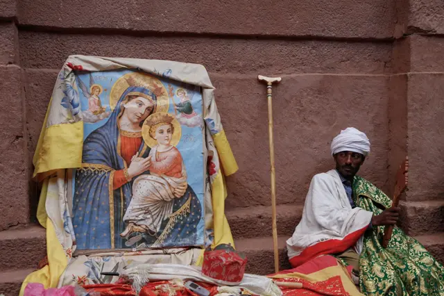 Sveštenik blagosilja vernike drvenim krstom kakav se redovno koristi prilikom verskih obreda, procesija, te tokom najvažnijih praznika među koje se ubraja i Gena, etiopski Božić.