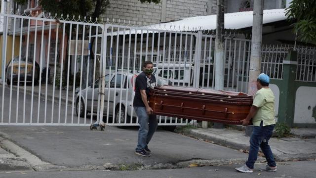 Deux hommes portent un cercueil dans les rues de Guayaquil, en Équateur