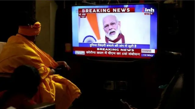 લૉકડાઉનના અહેવાલ જોઈ રહેલા સાધુની તસવીર