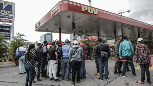 Gente haciendo cola en una estación de servicio.