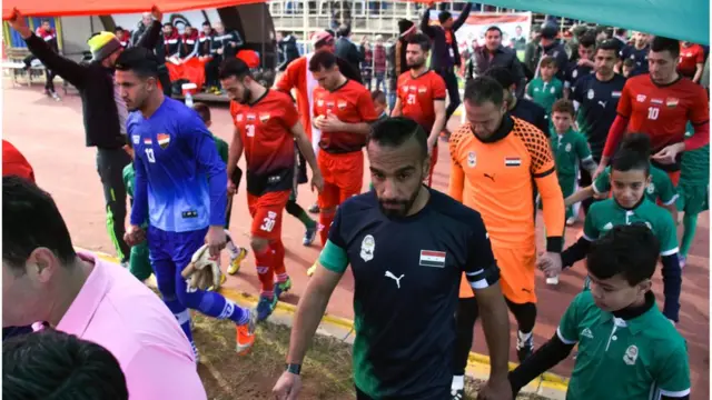 Players make their way on to the field from the sidelines before the game