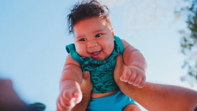 Mãos segurando um bebê no alto