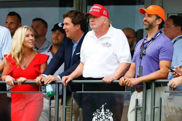 Tucker Carlson junto a Donald Trump como espectadores de un campeonato de golf en julio de 2022.