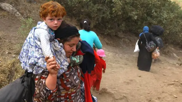 Mulheres Yazidis com crianças e sacolas