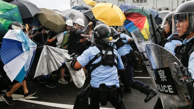 Police try to disperse protesters near a flag raising ceremony for the anniversary of Hong Kong handover to China in Hong Kong