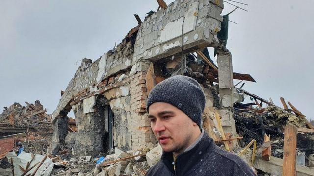 Un hombre frente a un edificio destrozado