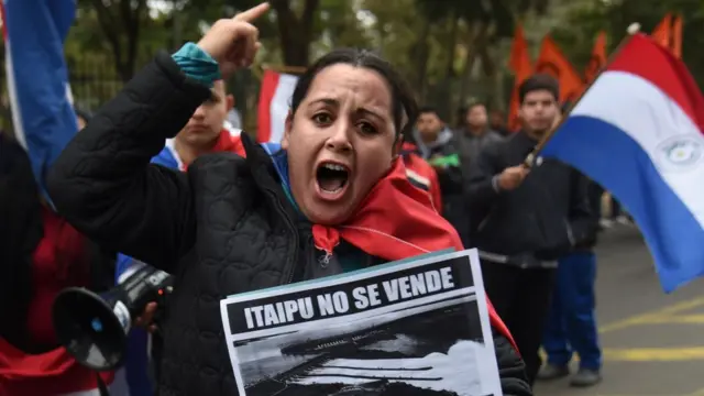 Manifestante com cartaz exibindo fotopoker teamhidrelétrica e dizeres: "Itaipu não se vende, Itaipu se defende"