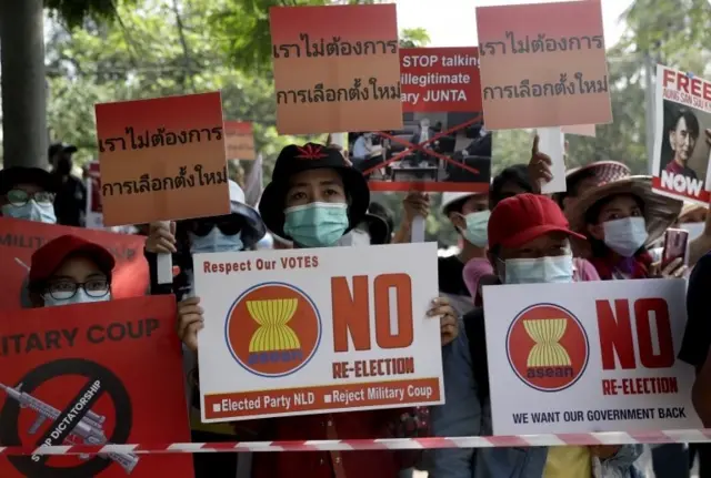 Demonstrators hold placards reading "We don"t need re-election" during a protest against the military coup, near the Embassy of Thailand in Yangon, Myanmar, 26 February 2021