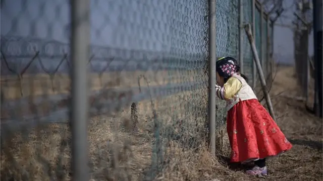 เด็กหญิงชาวเกาหลีใต้มองลอดรั้วดูเขตแดนของเกาหลีเหนือที่เขตปลอดทหาร (แฟ้มภาพ)