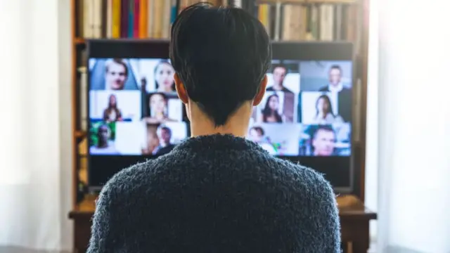 Un joven de espaldas mirando un televisor con Zoom.