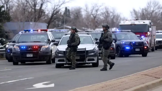 Law enforcement officers stand at the perimeter of a shooting site at King Soopers grocery store in Boulder, Colorado