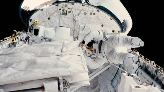 Sullivan, toda coberta por traje de astronauta, em nave no meio do espaço