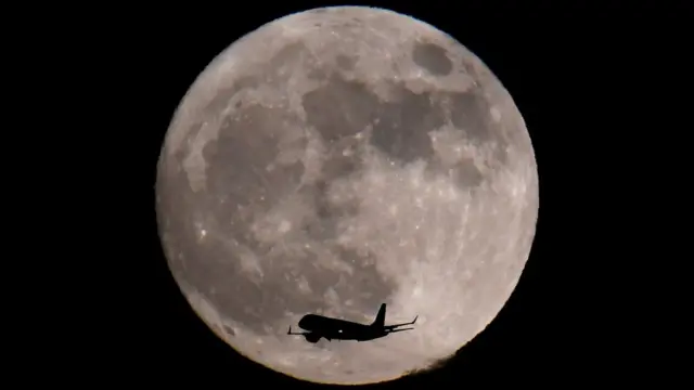 Un avión captado delante de la luna