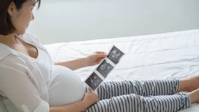 અલ્ટ્રાસાઉન્ડ રિપોર્ટને જોતી મહિલા