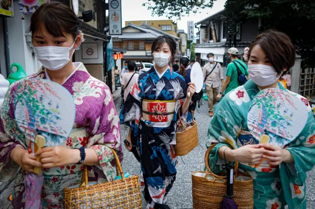 Des femmes portant des masques protecteurs marchent près du temple Kiyomizudera à Kyoto, au Japon.