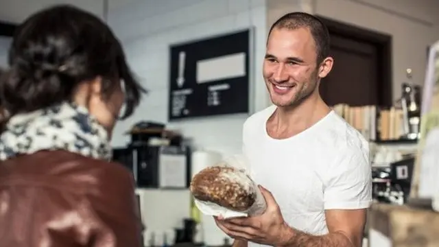 homem entrega pão para uma mulher