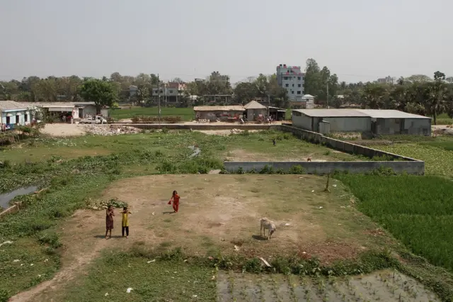 Deca pozdravljaju voz koji prolazi. Udaljavajući se od grada, urbanizovane zone počinju da zamenjuju pirinčana polja.