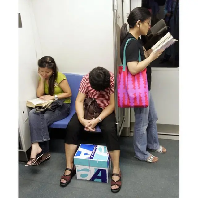 Pengguna MRT di Singapura membaca dalam perjalanan.