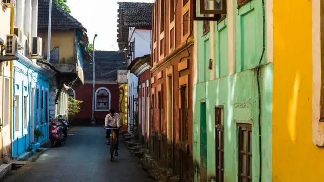 Un hombre en una bicicleta por una colorida calle de Goa