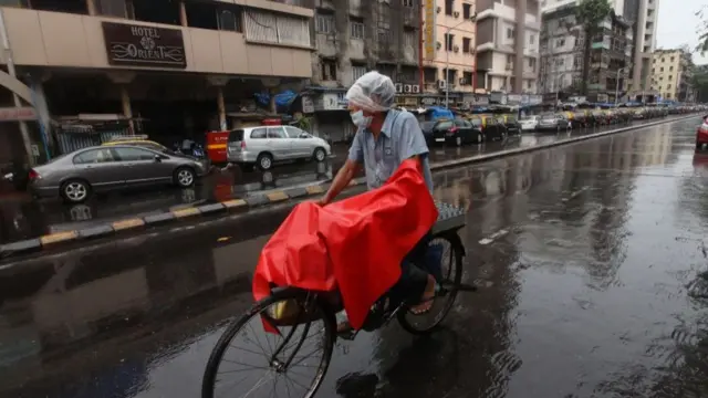 વરસાદમાં રસ્તા પર સાઇકલ ચલાવતી વ્યક્તિ