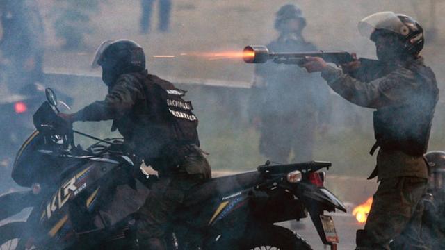 Policeman fires rubber bullet during a 2019 protest in Venezuela