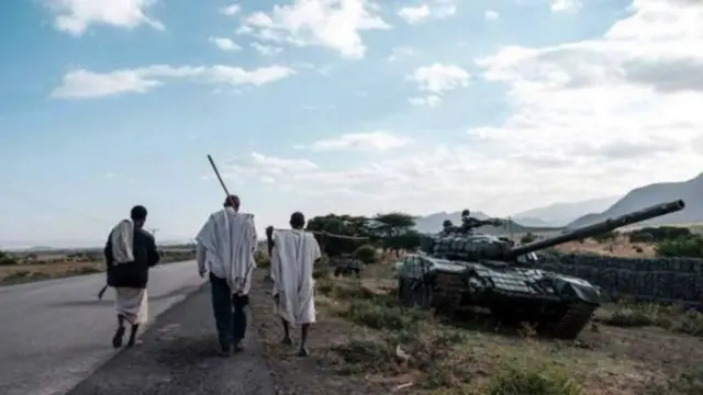 የተቃጠለ ታንክና በመንገድ ላይ ሚጓዙ ሰዎች