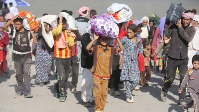 Displaced Iraqi families from the Yazidi community cross the Iraqi-Syrian border