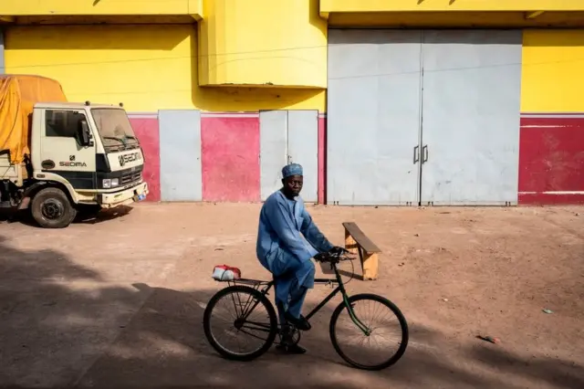 A man riding his bike in Ziguinchor looks into the camera.