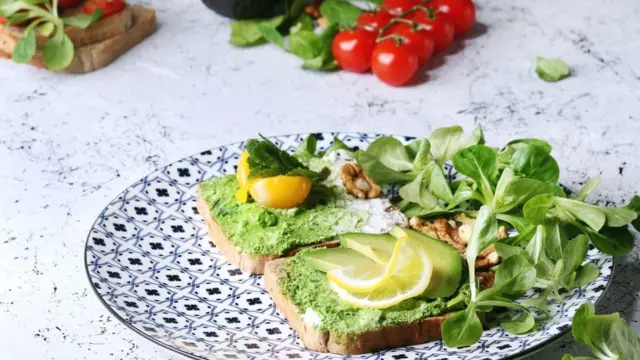 Sandwichs végétariens à l'avocat, à la ricotta, au jaune d'œuf, aux épinards et aux tomates cerises sur du pain complet grillé