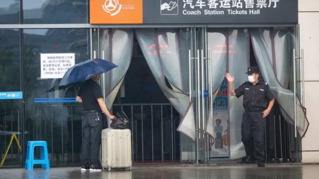 7月27日，南京汽车客运站暂停运营，在售票大厅门口，工作人员与前来乘车的乘客交谈。