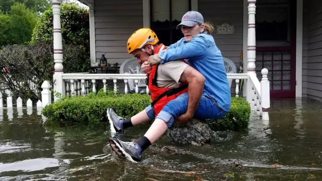 Un rescatista carga a una mujer en medio de una inundación tras el paso de la tormenta Harvey en Texas (EE.UU.)